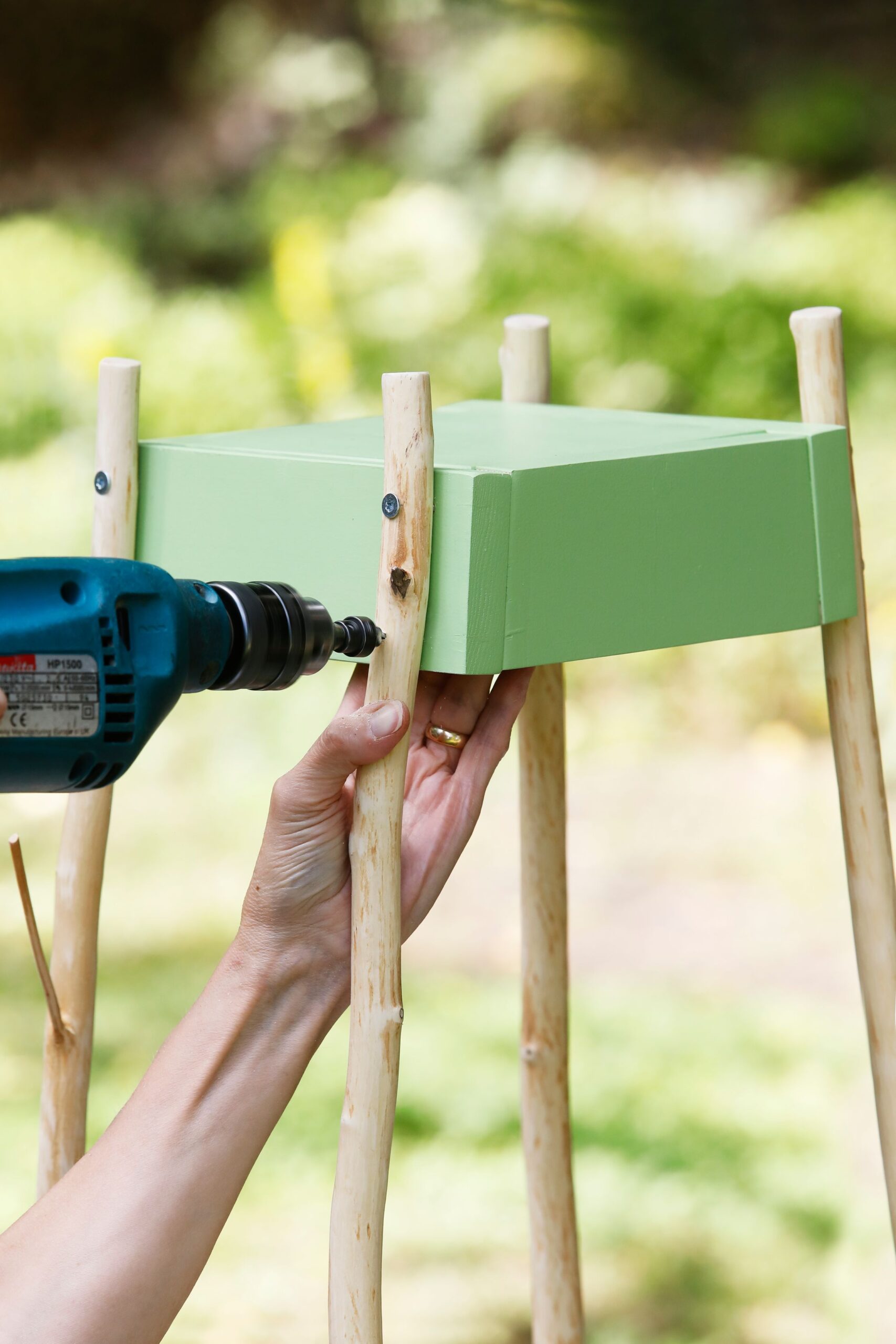 Nosta kukkalauta pystyyn. Levitä jalkoja aavistuksen, poraa alemmat reiät upotuksin ja kiinnitä ruuvit. Näin kiinnittäen jalat asettuvat viistoon sivulle ja ulospäin, jolloin kukkalauta seisoo tukevasti.